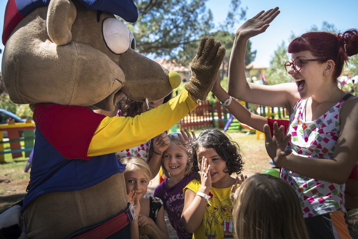 Maskottchen und Kinder beim High-Five-Spielen im Freien.