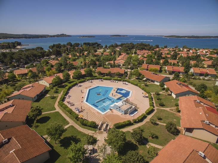Luftaufnahme eines Ferienresorts mit Pool und Häusern nahe der Küste.