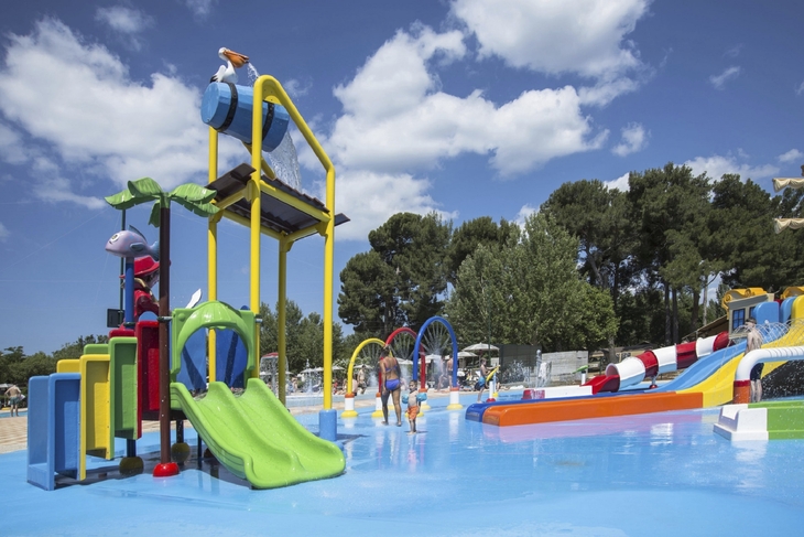 Wasserspielplatz mit bunten Rutschen und Spielgeräten unter blauem Himmel.