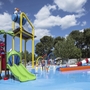 Wasserspielplatz mit bunten Rutschen und Spielgeräten unter blauem Himmel.