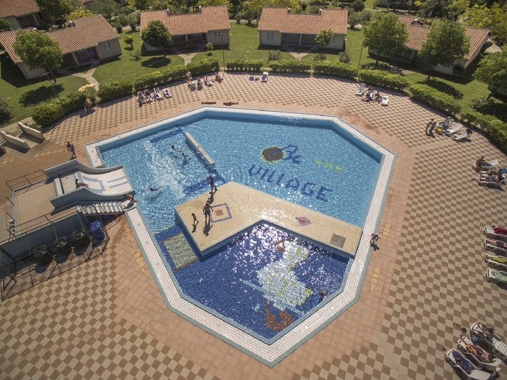 Im Ferienresort: Pool, Rutsche und entspannte Ferienhäuser im Hintergrund.