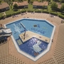 Im Ferienresort: Pool, Rutsche und entspannte Ferienhäuser im Hintergrund.