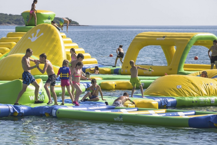 Personen spielen auf einem aufblasbaren Wasserpark im Meer.