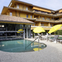 Außenbereich eines Hotels mit Pool, gelben Sonnenschirmen und mehrstöckigem Gebäude.