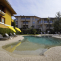 Hotelpool mit gelben Sonnenschirmen und Liegestühlen, umgeben von Gebäuden.