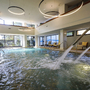 Innenpool mit Wasserstrahlen und Liegestühlen im Hotel.