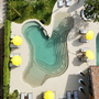 Luftaufnahme von zwei Pools und gelben Sonnenschirmen in einem Hotel in Bardolino.