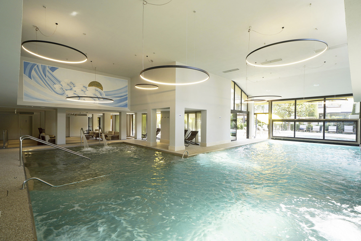 Innenpool im Hotel mit großen Fenstern und modernen Leuchten.