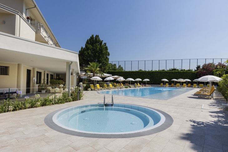 Swimmingpool-Bereich des Hotels mit Liegestühlen und Sonnenschirmen.