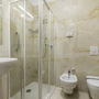Modernes Badezimmer mit Dusche, Waschbecken, WC und Bidet in hellem Design.