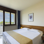 Hotelzimmer mit Doppelbett, Fenster mit Blick auf Balkon und Landschaft.