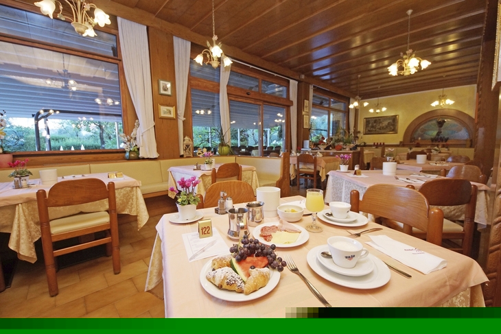 Hotelrestaurant mit gedeckten Tischen und einem Frühstücksteller im Vordergrund.