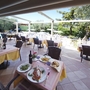 Restaurantterrasse mit gedeckten Tischen und Blick auf den Garten und Pool.