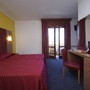 Hotelzimmer mit zwei Betten, Balkon, Schreibtisch und Stühlen.