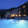 Hotel mit Pool bei Nacht in Malcesine, beleuchtet und umgeben von Liegestühlen.