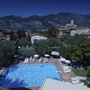 Blick von oben auf einen Pool mit Liegestühlen, umgeben von Bäumen und Häusern in Malcesine.