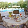 Frühstückstisch auf Terrasse mit Blick auf Pool und grüne Umgebung.