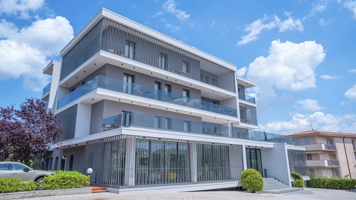 Modernes Hotelgebäude mit mehreren Etagen und Balkonen bei sonnigem Wetter.