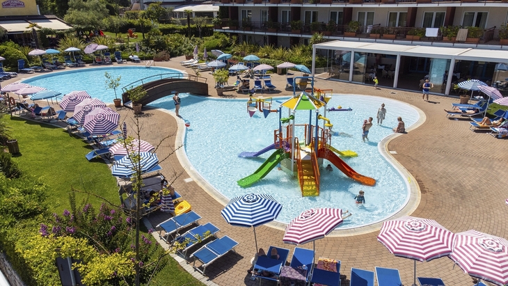Außenpool des Hotel Bella Italia mit Liegestühlen und Sonnenschirmen.