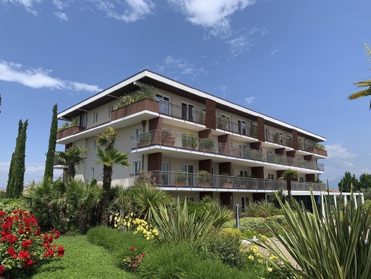 Fassade des Hotel Bella Italia in Peschiera del Garda mit Garten im Vordergrund.