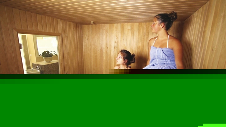 Zwei Personen entspannen in einer hölzernen Sauna.