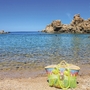 Strand mit türkisblauem Wasser und Felsen im Hintergrund in Costa Paradiso, Sardinien.