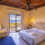 Hotelzimmer mit Balkonblick auf das Meer, Doppelbett und Holzmöbel.