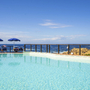 Pool mit Meerblick, blauer Himmel und Sonnenschirme im Hotel Costa Paradiso, Sardinien.