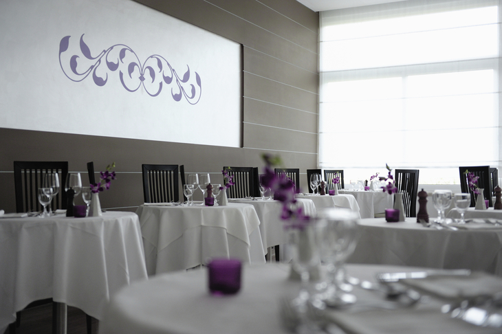 Elegantes Restaurant mit weiß gedeckten Tischen und lila Dekorationen.