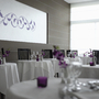 Elegantes Restaurant mit weiß gedeckten Tischen und lila Dekorationen.