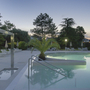 Beleuchteter Pool bei Nacht in einem Hotel mit umgebenden Pflanzen und Palmen.