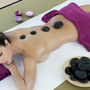 Frau bei Spa-Behandlung mit heißen Steinen auf dem Rücken.