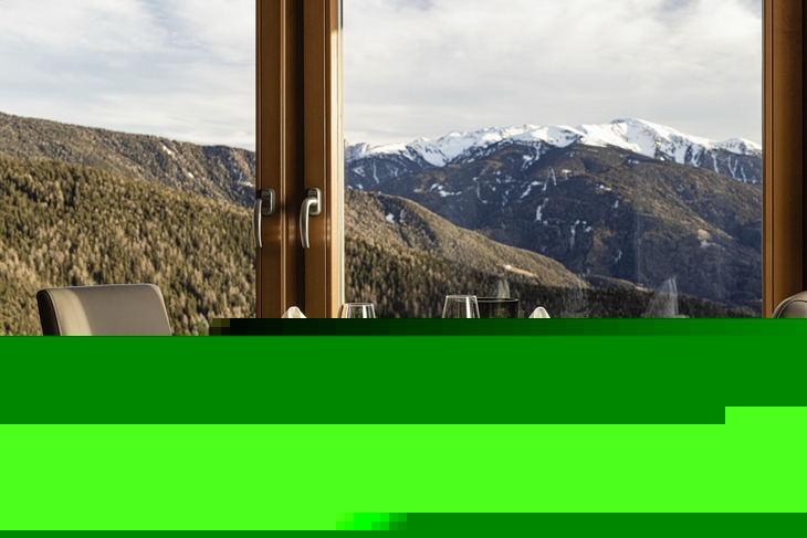 Gedeckter Tisch mit Bergblick durch großes Fenster.