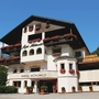 Hotel Mühlwald mit blumengeschmückten Balkonen vor blauem Himmel.