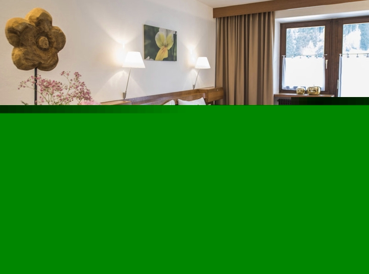 Gemütliches Hotelzimmer mit Doppelbett und Blumenarrangement.