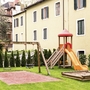 Spielplatz mit Schaukel und Rutsche vor einem Hotelgebäude
