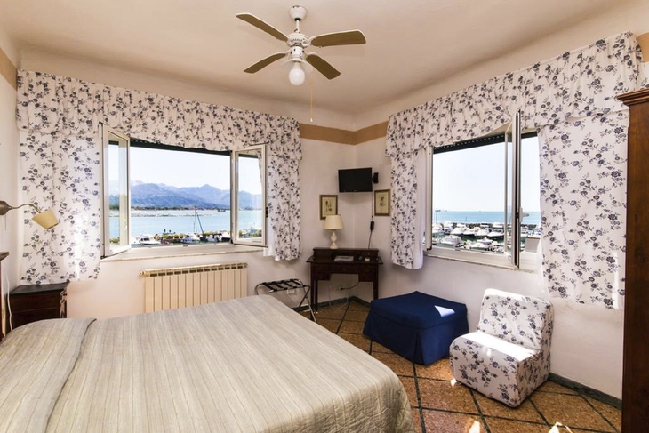 Zimmer mit Doppelbett und Meerblick durch zwei große Fenster.