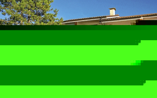 Außenansicht eines Ferienhauses mit Garten und Terrasse bei sonnigem Wetter.