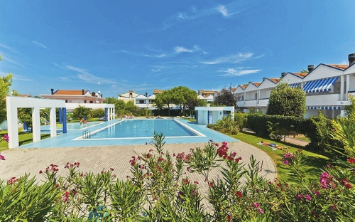 Pool und Ferienhäuser bei strahlend blauem Himmel im Villaggio Maja, Bibione.