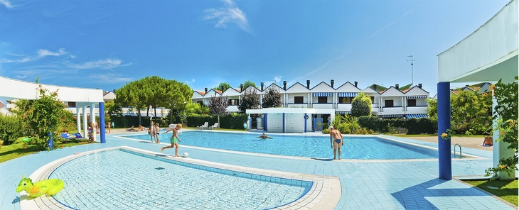 Panoramablick auf einen Pool mit Menschen und umliegender Ferienanlage in Bibione.