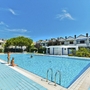 Poolbereich eines Ferienresorts mit Menschen und angrenzenden Gebäuden.