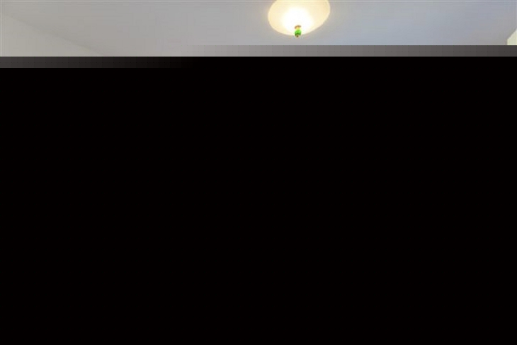 Schlafzimmer mit Doppelbett, Nachttischlampen, Fenster und buntem Wandbild.