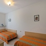 Zweibettzimmer mit orangefarbenen Betten und Bildern an der Wand.