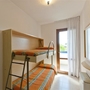 Zimmer mit zwei Etagenbetten, Fenster und orangefarbenen Bettdecken.