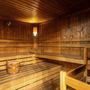 Innenansicht einer Holzsauna mit Bänken und einem Eimer auf der Bank.