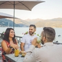 Gruppe von Freunden beim Aperitivo am Seeufer bei Sonnenschein.