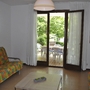 Wohnzimmer mit bunter Sitzecke und Blick auf Terrasse mit Gartenmöbeln.