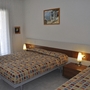 Hotelzimmer mit zwei Betten und bunten Tagesdecken, Flachbild mit Lampe.