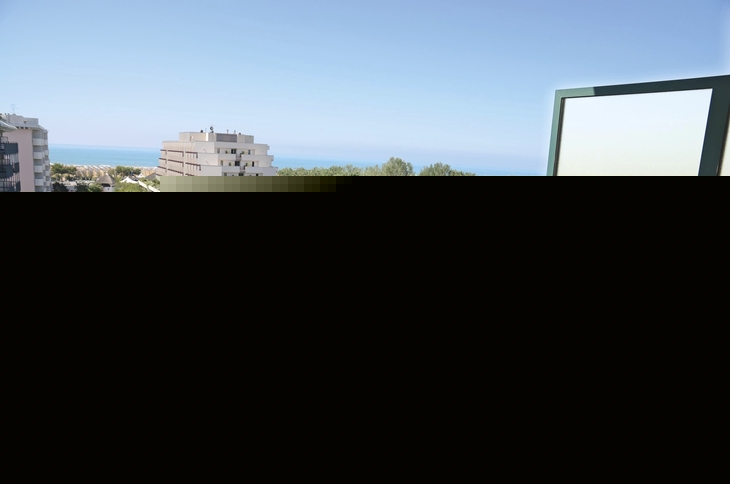 Balkon mit Tischen und Stühlen, Blick auf Gebäude und Meer in Bibione.
