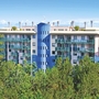 Ein mehrstöckiges Gebäude mit blauen Akzenten umgeben von Bäumen.